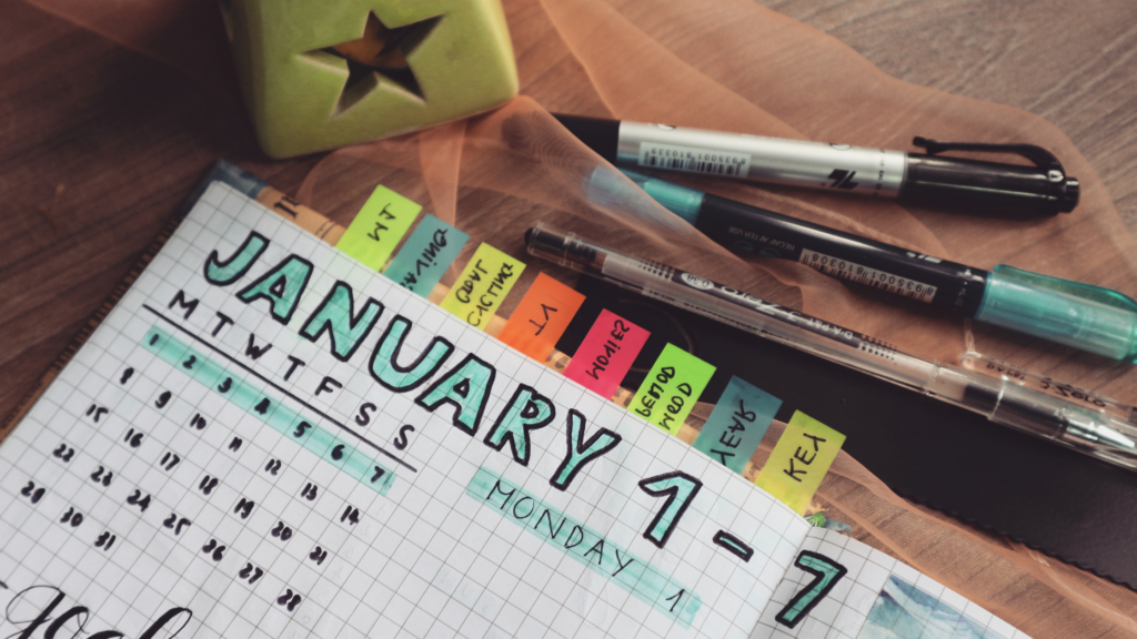 A bullet journal organized with planner tabs made from post it notes across the top